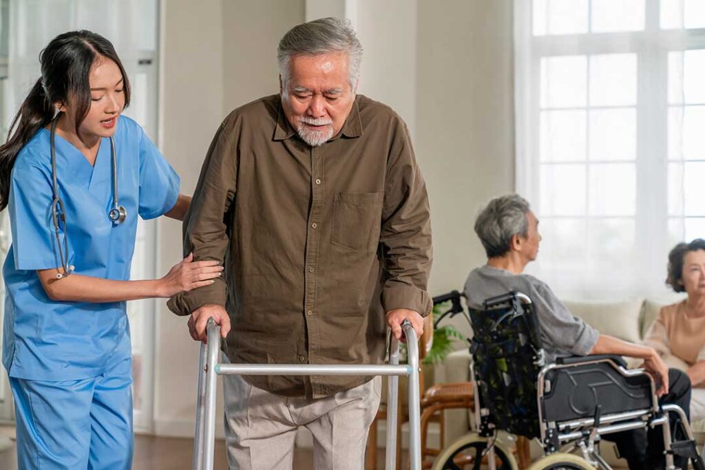 An assisted living staff member assisting an older adult with daily activities in a comfortable residential setting.