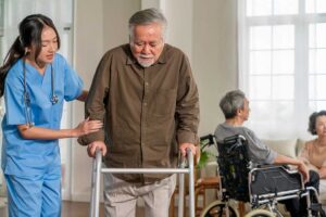 An assisted living staff member assisting an older adult with daily activities in a comfortable residential setting.